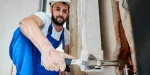 Homem consertando porta em casa alugada recentemente.